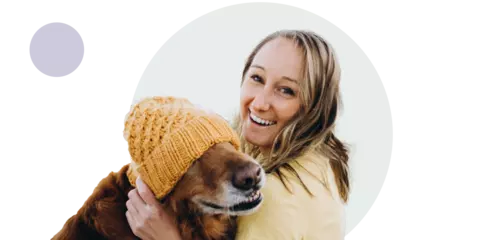 Glad tjej kramar om sin hund med mössa 