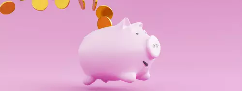 En rosa glad spargris som har guldmynt runt sig