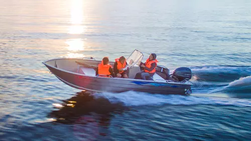 Tre personer åker i en lite båt på havet
