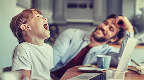 Dotter och far sitter vid köksbordet och äter frukost
