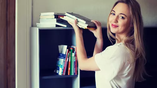 Tjej står med böcker vid en bokhylla