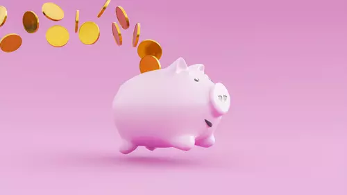 En rosa glad spargris som har guldmynt runt sig